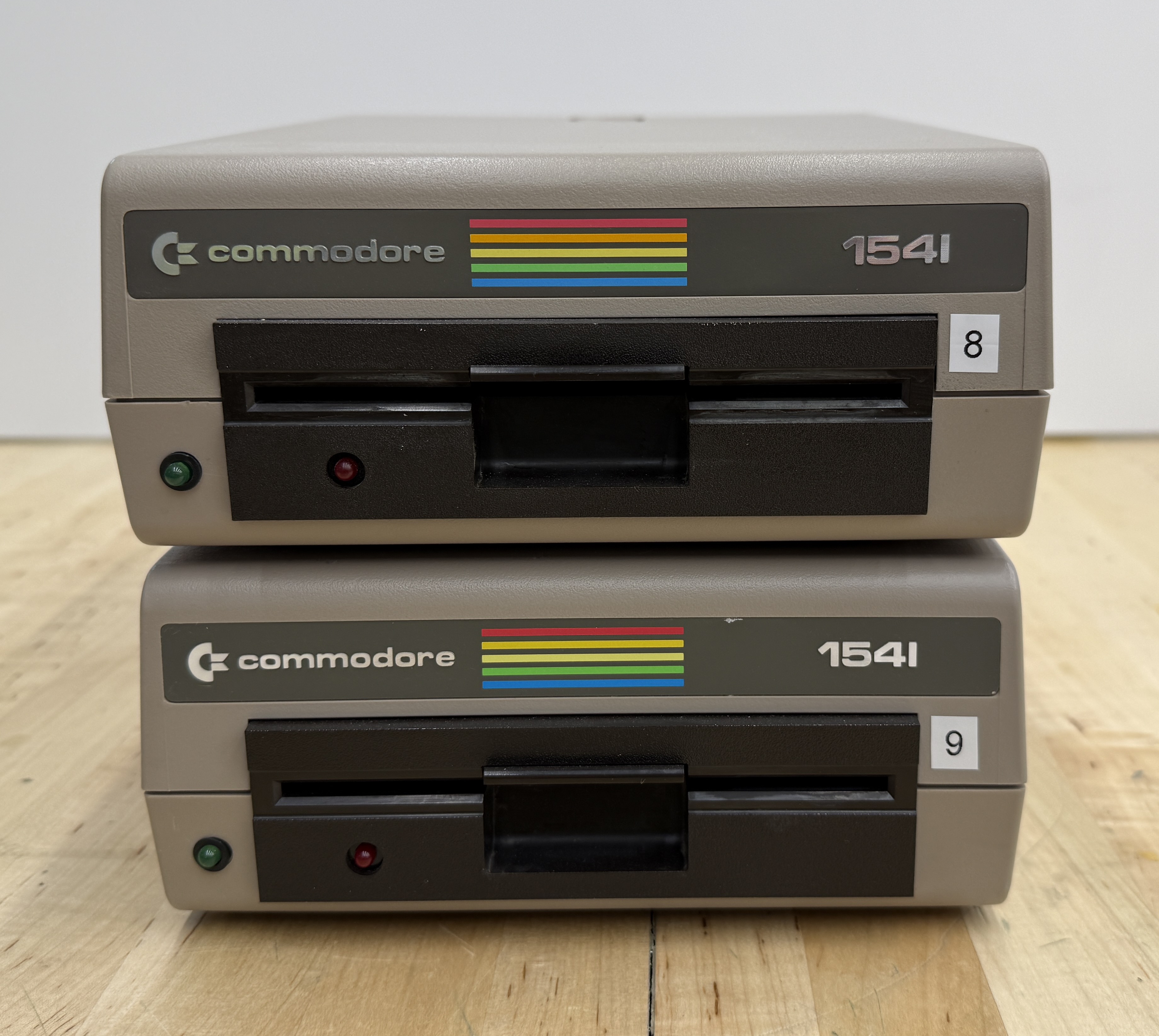Two stacked Commodore 1541 disk drives in beige cases with the rainbow Commodore badge, labelled 8 and 9 on the front