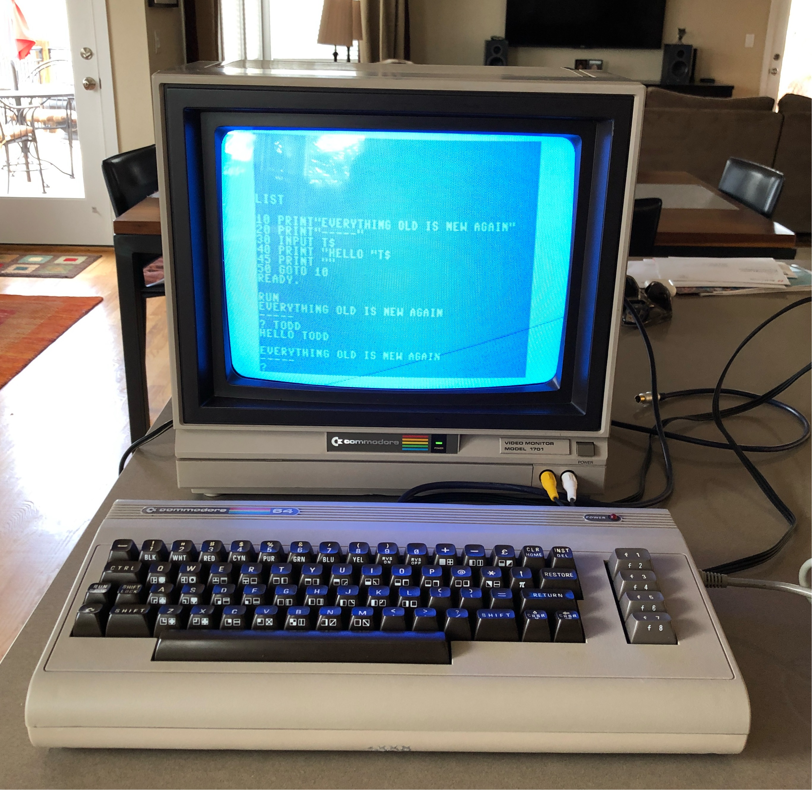 A restored Commodore 64 and 1701 monitor on a counter, the 1701 showing a BASIC program listing and the 'EVERYTHING OLD IS NEW AGAIN / HELLO TODD' output