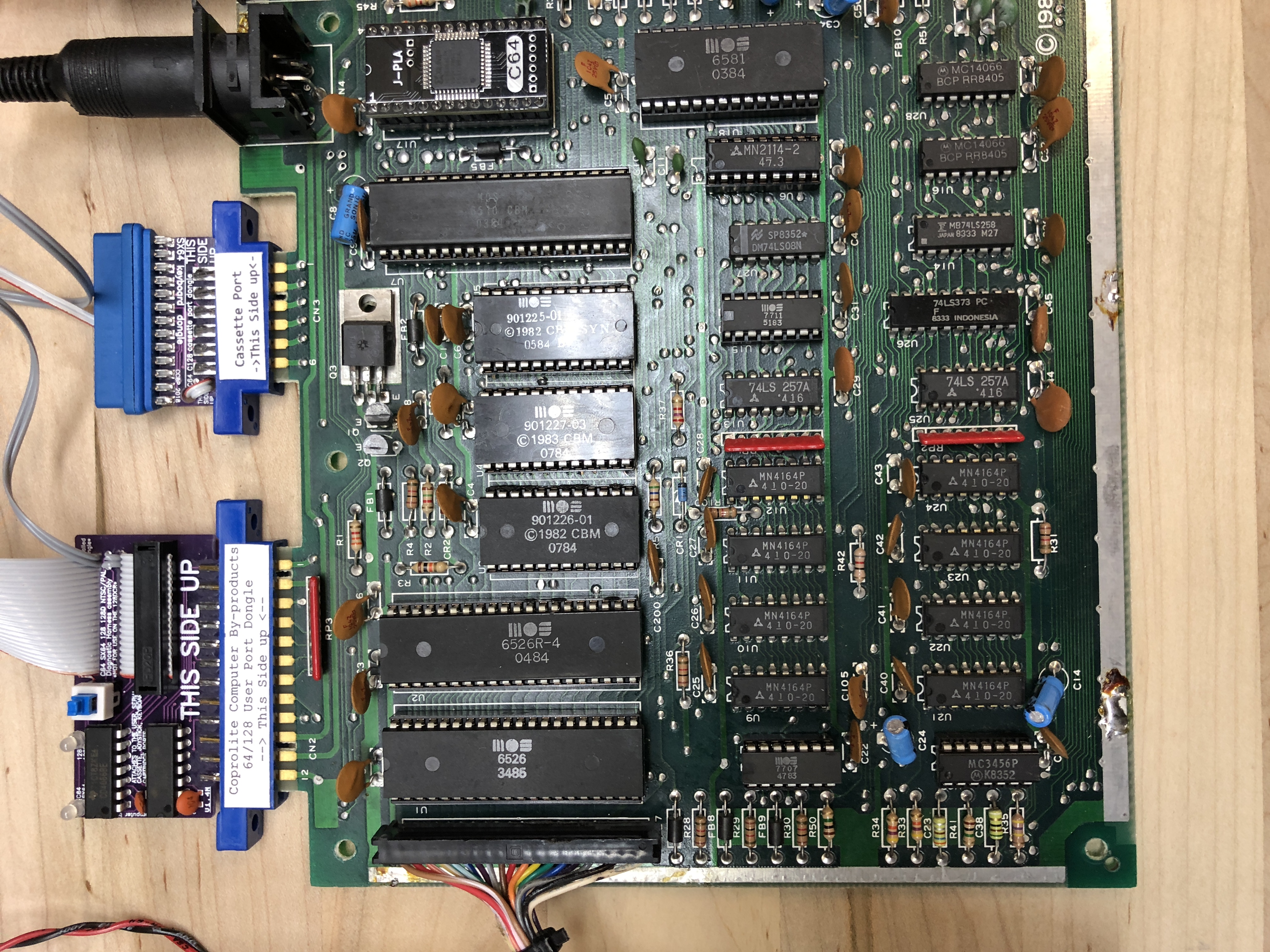 The motherboard set up on the bench with a dead-test cartridge and user-port loopback harness attached