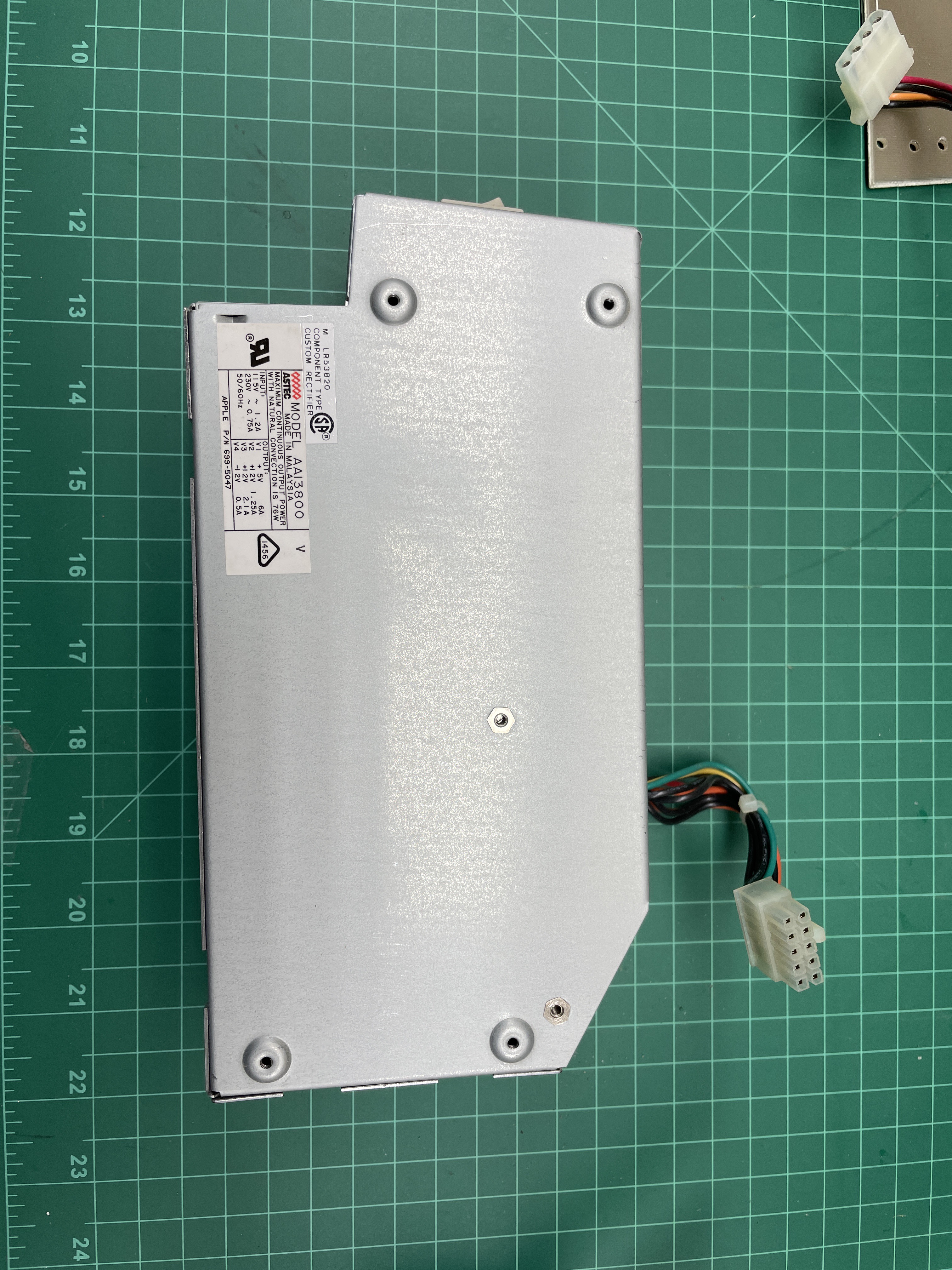 A brand-new sealed-steel replacement power supply for the Macintosh SE/30 on a green cutting mat