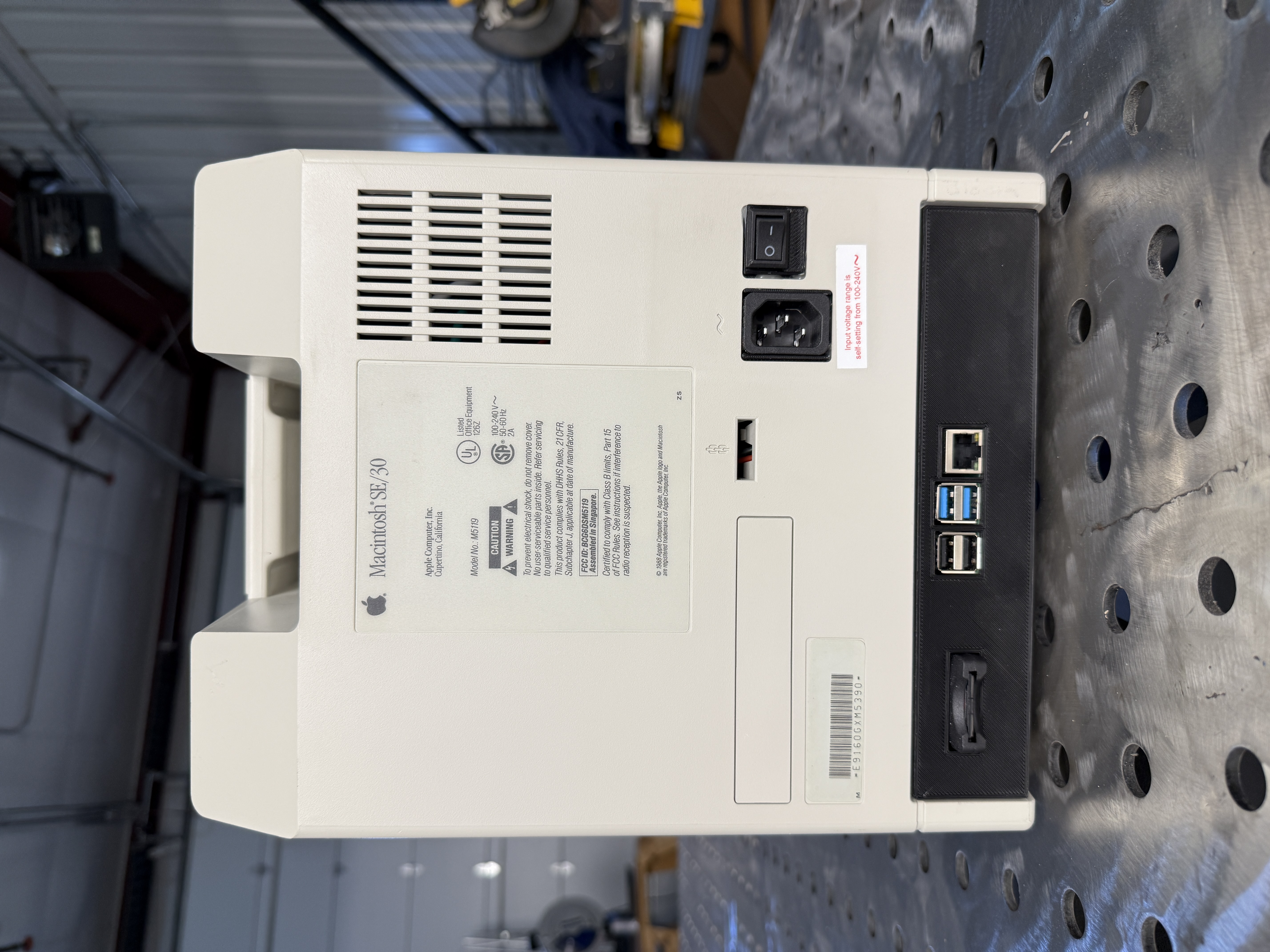 Dead-on back view of the reimagined SE/30 showing the original power inlet, rocker switch, and a modern port bezel carrying USB and Ethernet