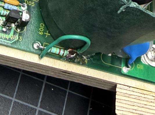 Closeup of the green insulated bodge wire emerging beside the C109 silkscreen and soldered to the resistor leg