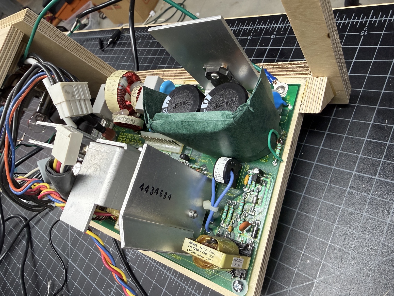 New C108 and C109 bulk capacitors wrapped in a green adhesive fish paper barrier on the main board, with the green bodge wire landing on a resistor leg nearby