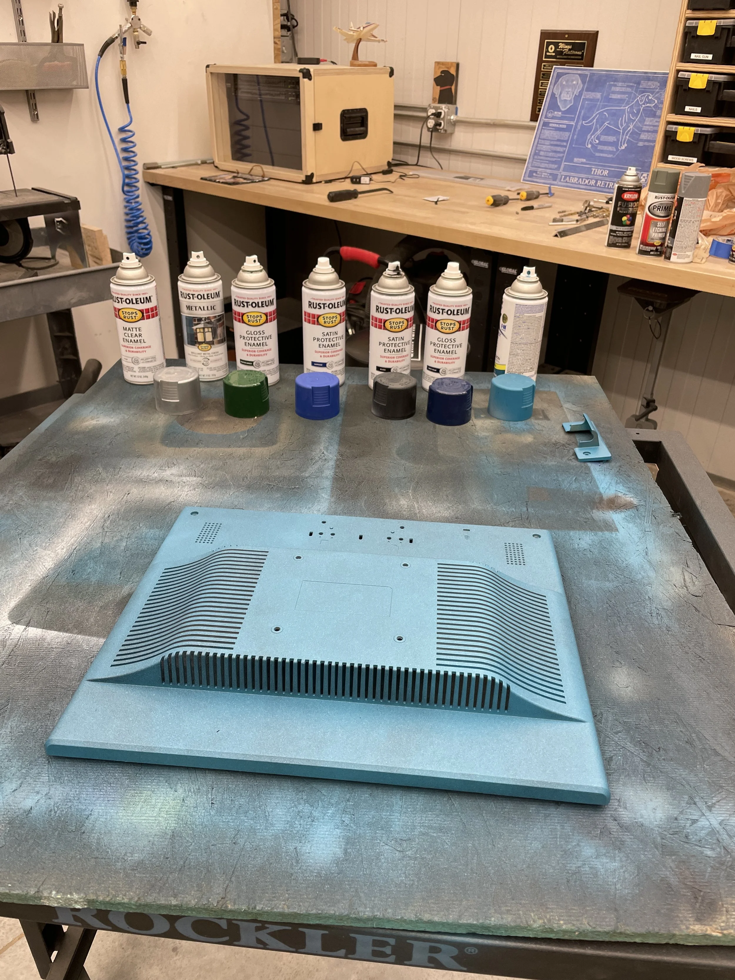 The primed top of the monitor with paint cans staged behind it, ready for color layering