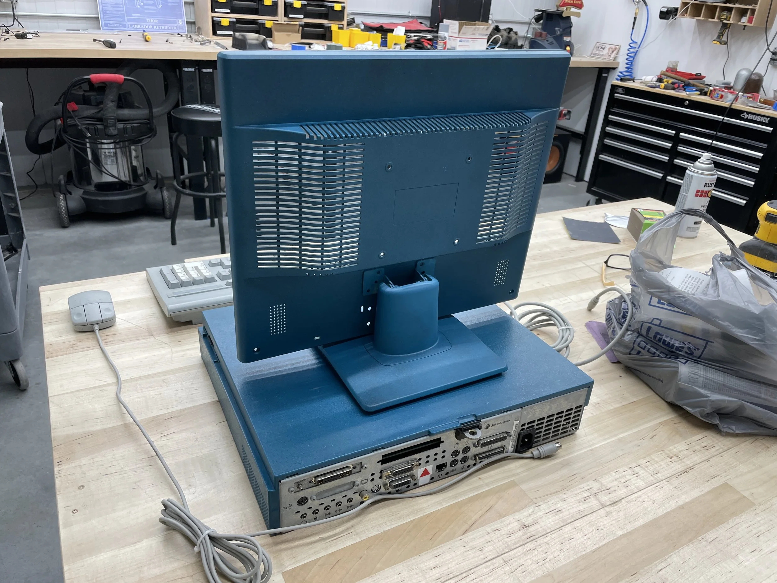 The completed teal monitor reassembled and sitting on top of the SGI Indy on the workbench