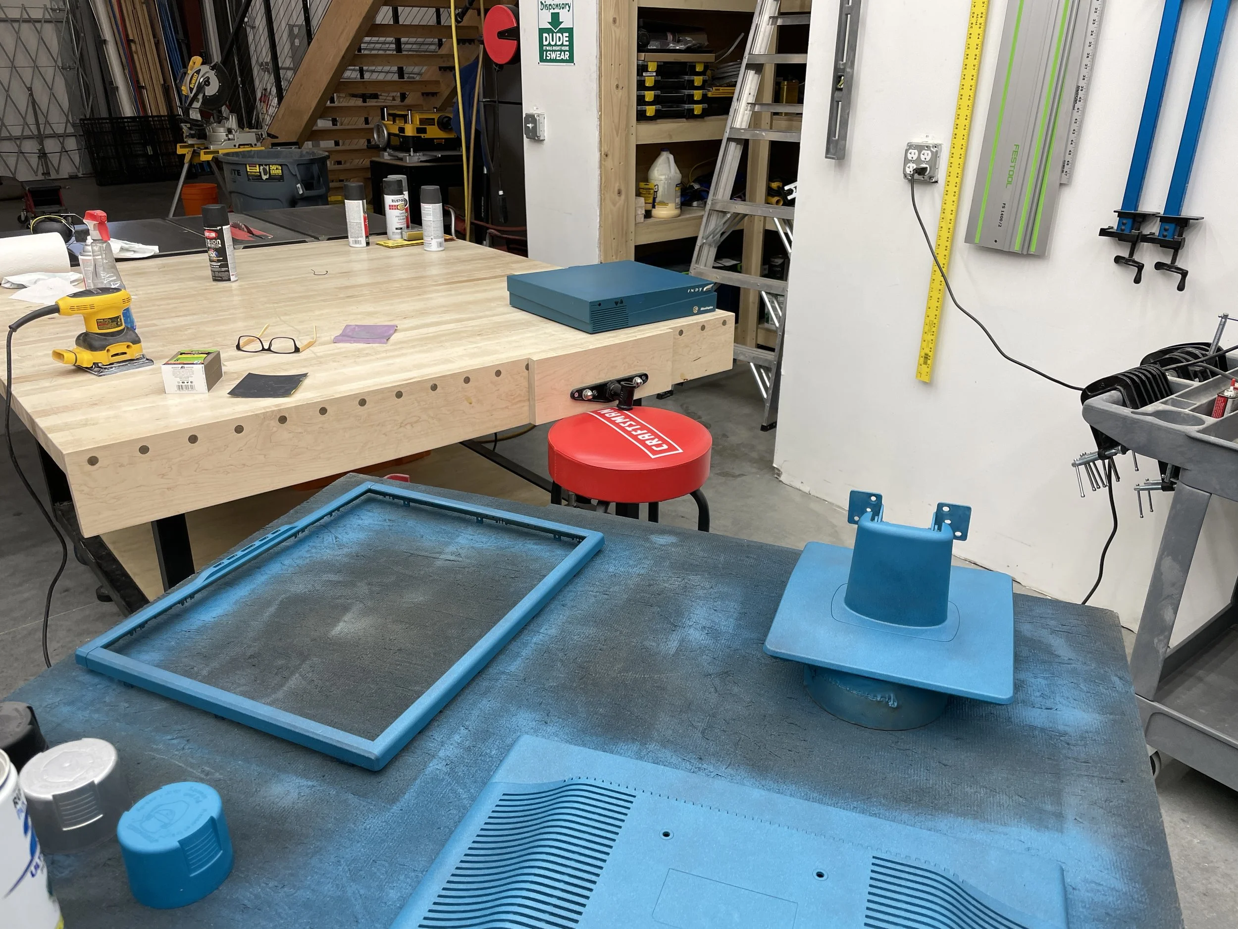 Mid-process: the stand, bezel frame, and rear chassis piece drying on the paint bench